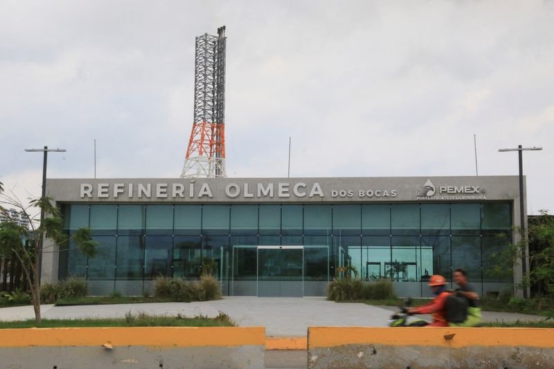 © Reuters. FILE PHOTO: Workers ride a motorcycle past one of the access to the state oil company Pemex